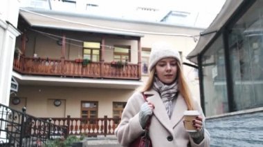 Beyaz önlüklü, genç ve güzel bir sarışın kasabada yürüyor, müzik dinliyor ve kahve içiyor. Şehirde bir yürüyüşün yavaş çekim görüntüleri.. 