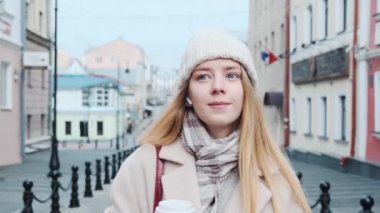 Beyaz önlüklü, genç ve güzel bir sarışın kasabada yürüyor, müzik dinliyor ve kahve içiyor. Şehirde bir yürüyüşün yavaş çekim görüntüleri.. 