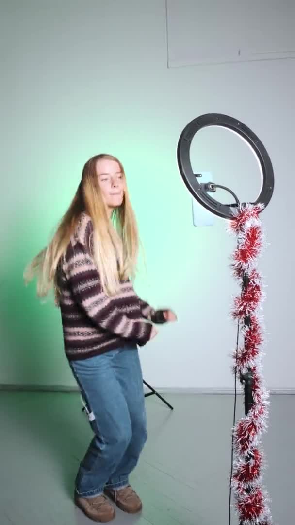 Seorang gadis dengan rambut putih menembak video untuk media sosial menggunakan telepon dan cahaya. Emosi di kamera. Gadis itu menari dengan kebahagiaan. — Stok Video