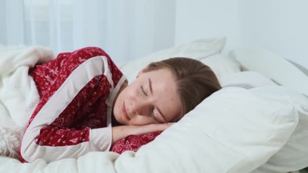 穏やかな若い女の子は、快適な居心地の良い柔らかい枕の上に新鮮なベッドで健全に眠り、朝までに健全な睡眠を楽しむ — ストック動画