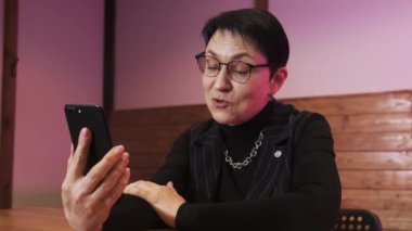 Telefonda elinde videoyla konuşan bir kadının yakın çekimi. Anne, kızıyla video bağlantısı üzerinden konuşuyor..