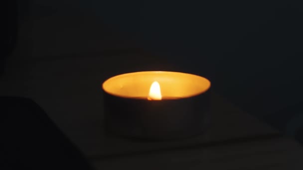 Nahaufnahme einer kleinen Kerze, die vor dunklem Hintergrund brennt. — Stockvideo