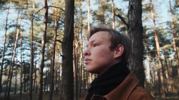 Un giovane fotografo maschio biondo fotografa la natura. Fotografo scatta foto nel bosco con una macchina fotografica retrò. Giovane fotografo vestito in stile retrò. — Video Stock