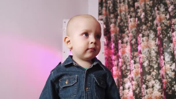 Portrait of a young child playing on a sofa against the background of a bright lamp. Close-up of a beautiful, happy child. — Stock Video