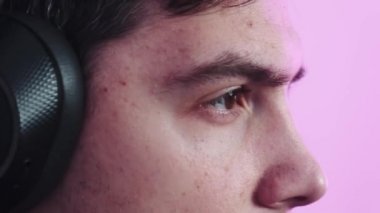 Genç bir adam kablosuz kulaklığını takıyor ve bilgisayar oyunları oynuyor. Adam müzik dinliyor, oyunlar oynuyor ve uzaktan çalışıyor.. 