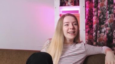 Kanepede oturup gülen güzel gözlü genç bir kızın yakın çekimi. Keyfi yerinde güzel bir kızın portresi..