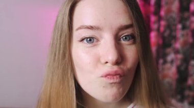 Güzel gözleri olan genç bir kızın kameraya baktığı yakın çekim. Güzel bir kızın portresi ve ağır çekimde yumuşak bir kayış..