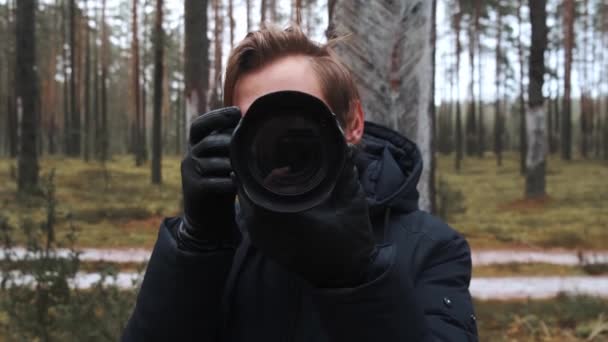 Eine weite Einstellung, während der Fotograf das Bild aufnimmt. Der Fotograf drückt im Wald den Auslöser. — Stockvideo