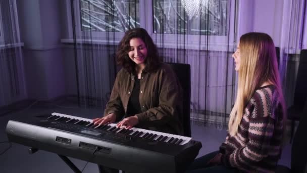 Deux jeunes femmes pratiquent leur chant avec un piano. Une enseignante apprend à son élève à vocaliser. L'élève et l'enseignant apprennent une nouvelle chanson. — Video