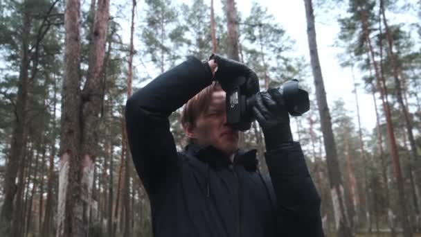 Seorang fotografer mengambil gambar di hutan, seorang pemuda mengambil gambar di hutan dengan kameranya. Alam yang indah melalui mata seorang fotografer. — Stok Video