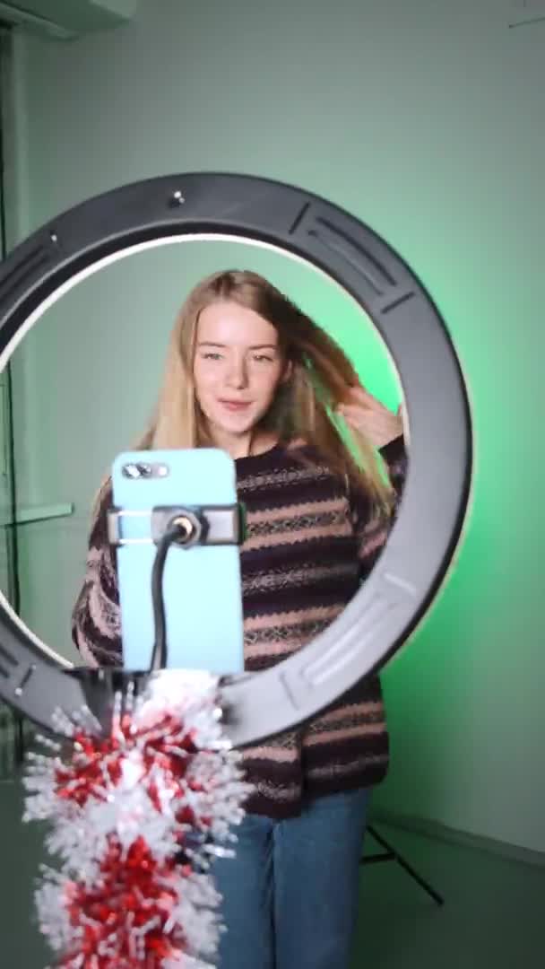 Seorang gadis dengan rambut putih menembak video untuk media sosial menggunakan telepon dan cahaya. Emosi di kamera. Gadis itu menari dengan kebahagiaan. — Stok Video