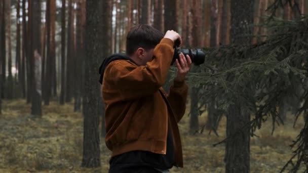 A photographer takes pictures in the woods, a young man takes pictures in the woods with his camera. Beautiful nature through the eyes of a photographer. — Stock Video