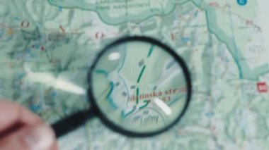 Haritaya bakmak için kullanılan büyüteç yakın plan. Büyüteçle büyütülmüş cam kullanırken haritadaki yönlere bakılıyor. 