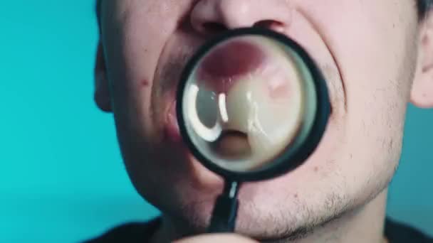 Denti attraverso una lente d'ingrandimento. Denti attraverso una lente d'ingrandimento su uno sfondo blu. Video 4k di alta qualità — Video Stock