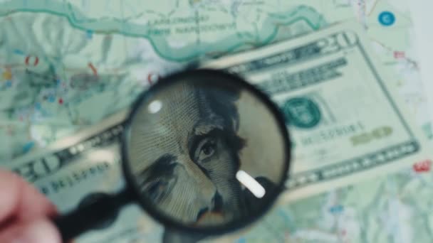 Gros plan sur les dollars qui sont sur la carte. Les dollars sont regardés sous une loupe. — Video