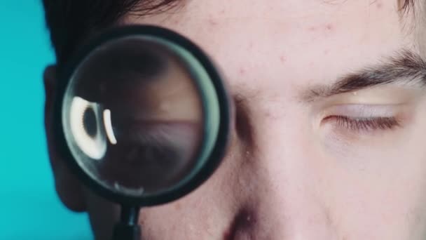 A man looks through a magnifying glass. Big eye through a magnifying glass against a bright background. High quality 4k video — Stock Video