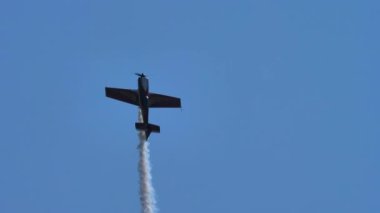 Aerobatik uçak dikey olarak tırmanıyor, yarım bir döngü yapıyor ve onu ekran takip ediyor.