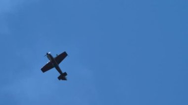 Küçük pervaneli akrobatik uçak ters uçuş ve beyaz duman izi var.