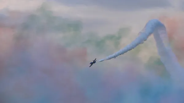 Aerobatic plane with white trail in the sky still full of colorful smoke — Stock Photo, Image