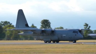 Hava üssünden havalanan C-130 askeri kargo uçağı mavi gökyüzü güneşli bir günde havalanıyor.