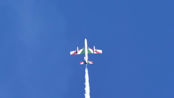 Plane rises vertically into blue sky, stops and falls back into its white smoke — Stock Video