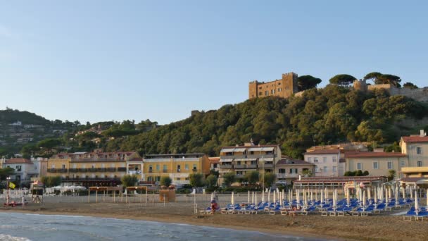 Spiaggia al tramonto con cuffie chiuse dominata da una collina con castello medievale — Video Stock