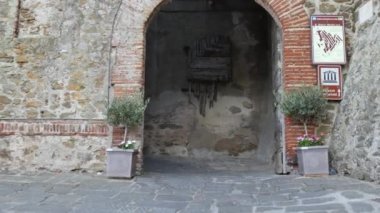 Antik bir kalenin kemerli taş kapısından içeri girerek
