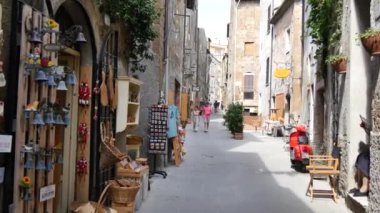 Pitigliano şehir merkezindeki dar ortaçağ taşlarından caddelerde yürüyor.