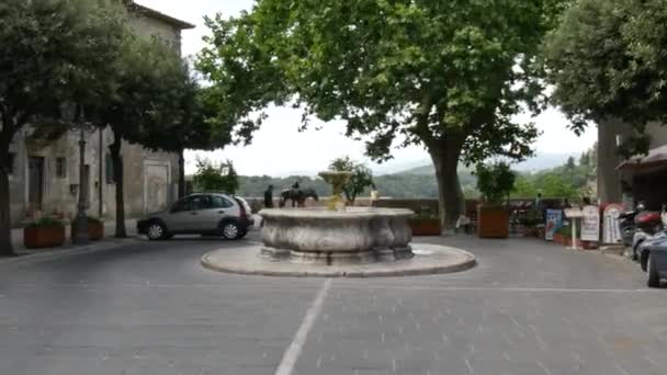 Small historic square surrounded by trees with a white marble fountain in the center — Stock Video