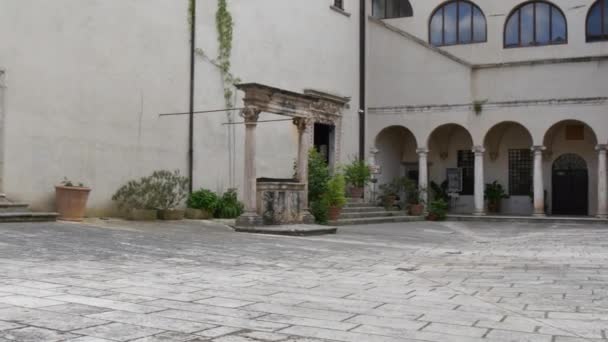 Interior de um edifício histórico com arcadas e janelas arqueadas e um poço de pedra — Vídeo de Stock