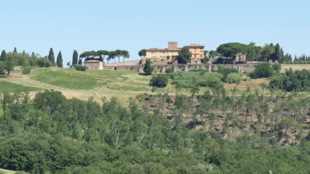 Agricultural farmhouse on the top of a green Tuscan hill surrounded by vineyards — Stock Video