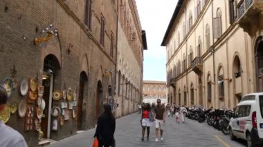 Şehir merkezinin dar eski bir caddesinde yürüyen turistlerin olduğu Siena kentsel manzarası