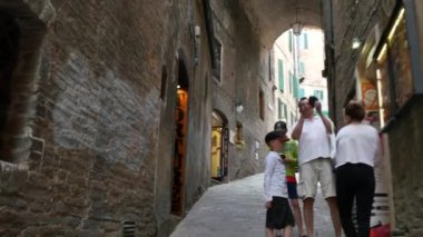 Siena 'nın tarihi merkezinde bir sokakta yürüyen ve fotoğraf çeken turistler