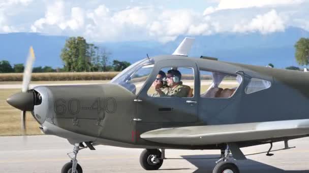 Kleine propeller militaire vliegtuig rolt op de baan met twee piloten aan boord — Stockvideo