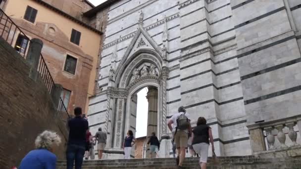 Turistit kiipeävät portaita, jotka johtavat Sienan katolisen katedraalin ovelle — kuvapankkivideo