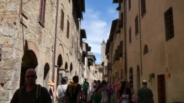 Turistler San Gimignano 'nun ünlü Tuscany tatil beldesinde yürüyorlar.