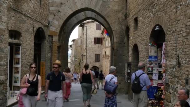 Passeggiando sotto un'antica porta ad arco in mattoni rossi nelle mura di San Gimignano — Video Stock