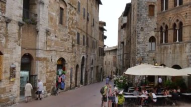 Turistler San Gimignano 'daki caddelerden birinde bir restoranda yemek yiyorlar.