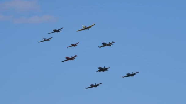 Формирование девяти военных реактивных и пропеллерных самолетов в полете в голубом небе — стоковое видео