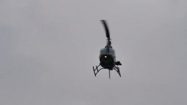 Küçük askeri helikopter gri bulutlu gökyüzünde uçuyor