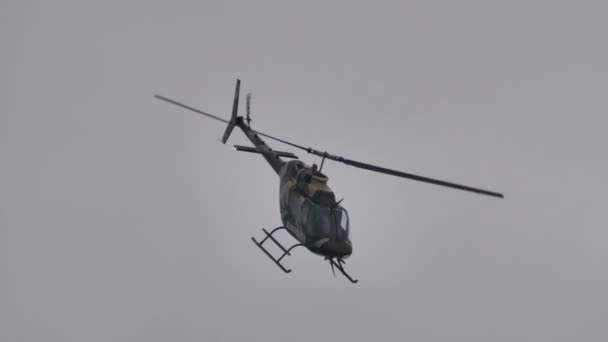 Hélicoptère militaire en vol à grande vitesse par mauvais temps gris — Video