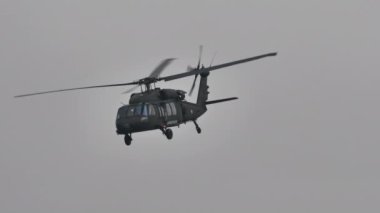 Sikorsky S-70 Kara Şahin askeri helikopteri geçiyor ve dönüyor.