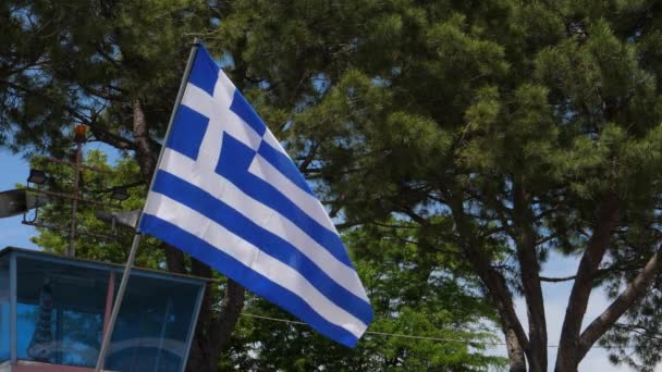 Griekse vlag zwaaien in de wind 4K Ultra HD Video met groene bomen achtergrond — Stockvideo