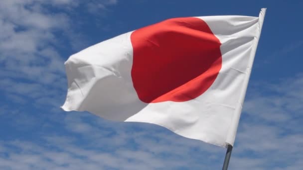 Japanse vlag zwaaien in de wind in slow motion close-up met lucht achtergrond — Stockvideo