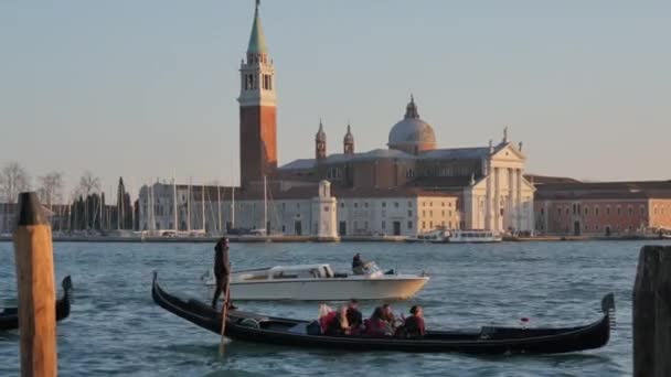 Gôndola no Canal Grande de Veneza ao pôr-do-sol hora dourada com a igreja no fundo — Vídeo de Stock
