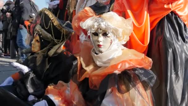 Onherkenbare vrouw met wit gezichtsmasker in oranje en zwart op Venetië Carnaval — Stockvideo