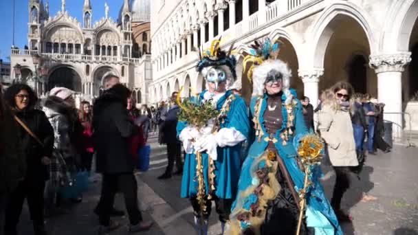 Pár s modrým karneval drees a maska stojící lidé bloudí v pozadí — Stock video
