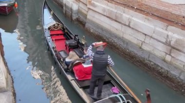 Gondolcu turistleri bir gondolla Venedik, İtalya 'daki dar bir kanala götürüyor.