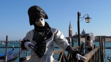 Elinde vantilatörle kameraya poz veren siyah beyaz karnaval kostümlü adam.