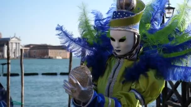 Maskierte Person im Fantasie-Karnevalskostüm hält eine Goldkugel im Karneval von Venedig